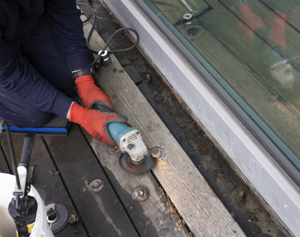A close up of a Maintenance team member grinding down bolts on the decks outside of the Tearoom. 