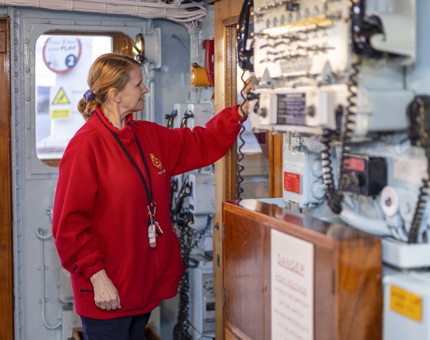  A Housekeeper is in the Royal Yacht Britannia's Bridge cleaning a glass panel. 