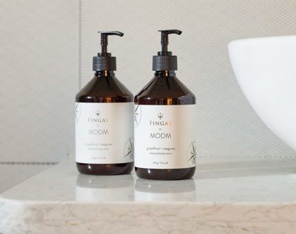 Two bottles of hand and body lotion on a bathroom counter. 