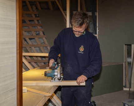 A Maintenance man cutting a plank of wood at Fingal in Leith. 