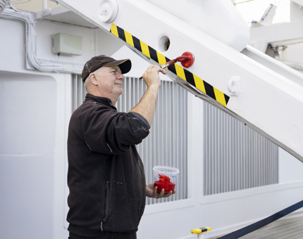 A Maintenance man is Painting The Plugs In The Davits Red
