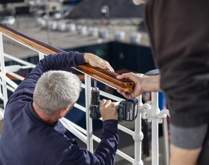 Maintenance team members using a power drill to secure a handrail in place. 