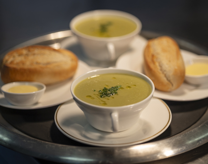 Two bowls of leek and potato soup and bread rolls. 