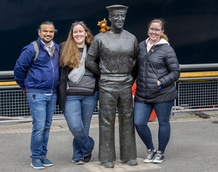 Visitors stand next to a life-size statue of a former Royal Yachtsman. 