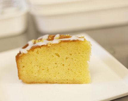 A slice of lemon drizzle cake is sitting on a white plate in Britannia's Tearoom. 