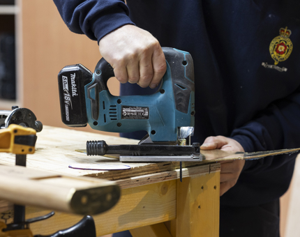 A Maintenance team member is using a cordless jigsaw to cut brass ends for handrails at Britannia's sister ship Fingal Hotel. 