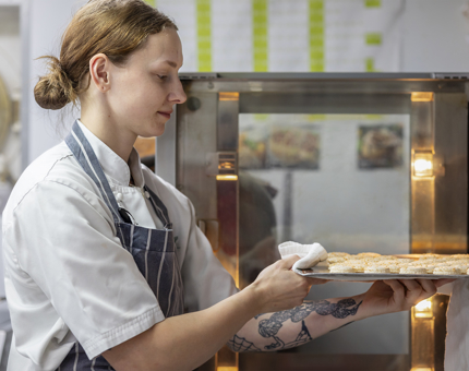 A Chef removing a tray of macarons from the oven. 