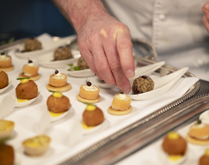 A close up of a chef placing canapes onto a tray. 