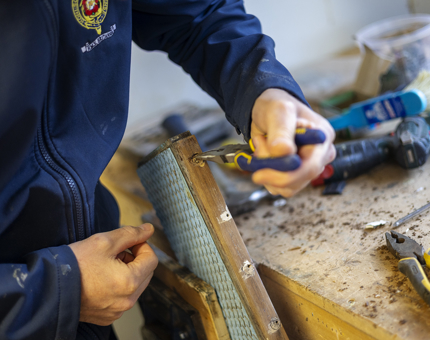 A close up of hands removing screws from a section of steps from onboard Britannia. 