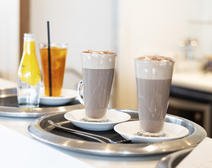 Tray with Hot Chocolates With Marshmallows and an Iced tea are on the Bar In The Tearoom aboard Britannia. 