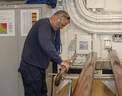 A Maintenance team member sanding wooden handrails. 