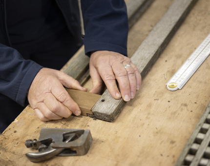 A close up of hands assembling wood pieces together. 