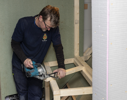 A Maintenance man is cutting a piece of wood aboard Fingal Hotel in Leith. 
