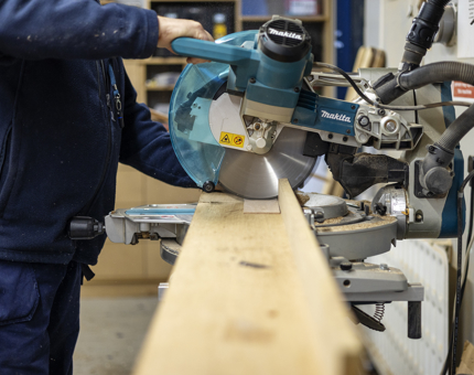 A close up of a Maintenance man Cutting Wood. 