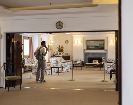 A man is listening to the audio guide handset in the State Drawing Room on Britannia in Edinburgh. 