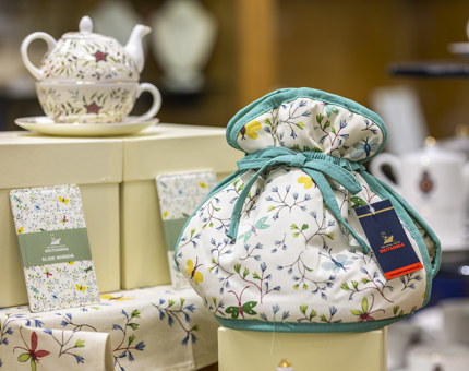 A selection of the embroidery range of products in the Gift Shop. There is a tea set, tea cosy, tea towels. 