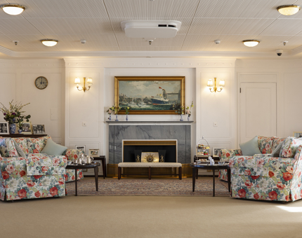 The State Drawing Room. There are floral covered couches, with side tables and a fire place.