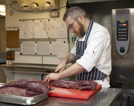 A Chef in the Galley slicing beef. 