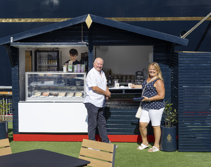 Two visitors stand at the new Tea on the Quay cafe hut next to The Royal Yacht Britannia. 