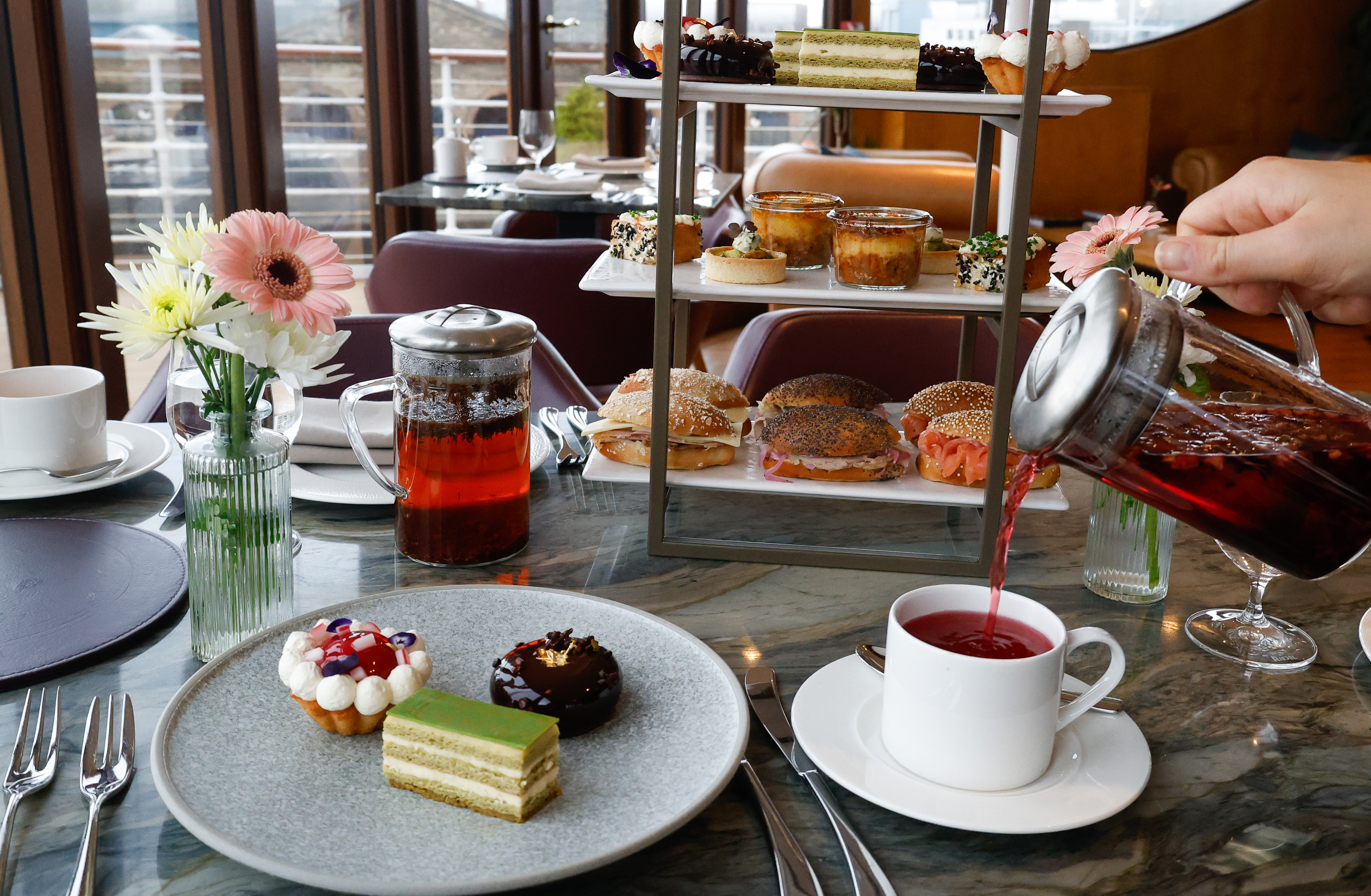 A table is set with a tiered afternoon tea stand with cakes, sandwiched and savouries on it in the Lighthouse Restaurant in Leith.