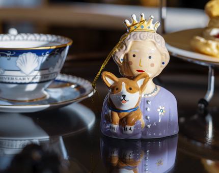 A hanging decoration of Queen Elizabeth II holding a corgi. 