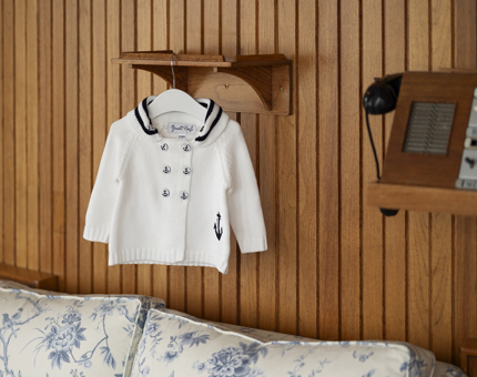 A children's cardigan in the style of a white and blue sailor's outfit. 