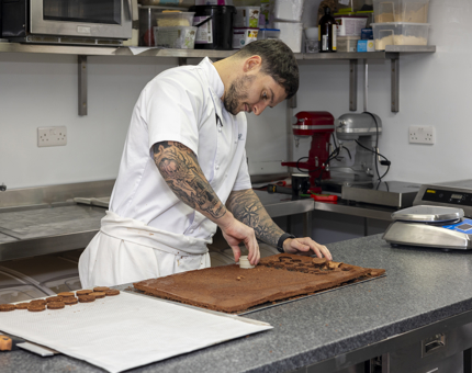 A Chef is in the Galley aboard Britannia in Leith preparing chocolate to go with a dessert. 