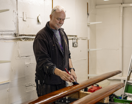 A Maintenance team member varnishing handrails. 
