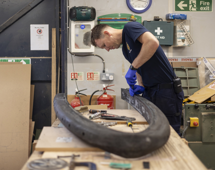 A Maintenance man at a work bench cleaning up the surround from the Admiral's Fast Motor Launch boat. 