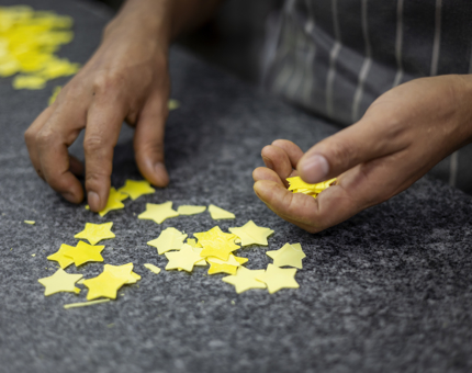 A close up of a Chef'd hands picking up yellow chocolate stars. 