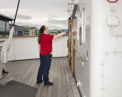 A Housekeeper is using a duster to Clean the Bridge Before Opening