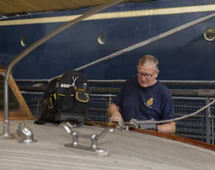 At the Royal Barge, a Maintenance man is removing varnish with a heat gun.