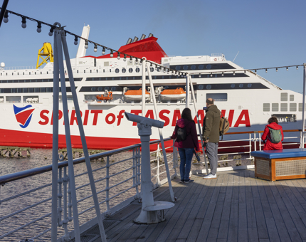 On Britannia's Verandah Deck, visitors watch as a large ship leaves the Port of Leith. 