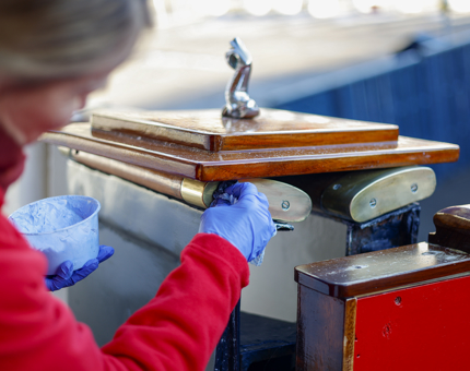 A close up of a Housekeeper polishing brass railings on the Royal Brow on The Royal Yacht Britannia. 