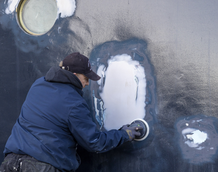 A Maintenance team member sanding the side of Britannia. 