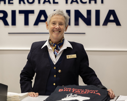 A smiling Shop Assistant standing behind the tills.