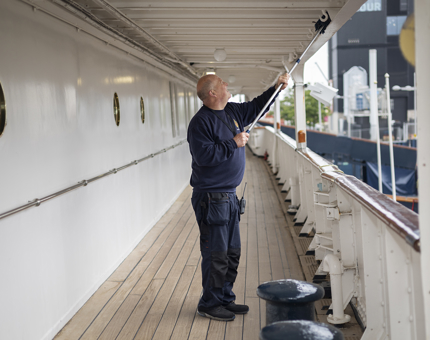 A Facilities Officer cleaning the deck with a duster. 