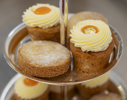 A close-up of small carrot cakes and shortbread on a silver cake stand. 