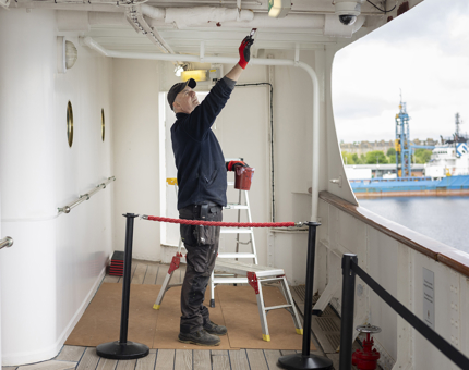 A Maintenance team member adding a coat of paint to a sheltered portion of the deck.